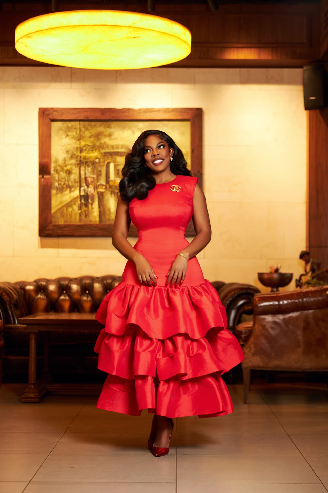 Nana Aba Anamoah standing in a red tiered dress in an art-filled room