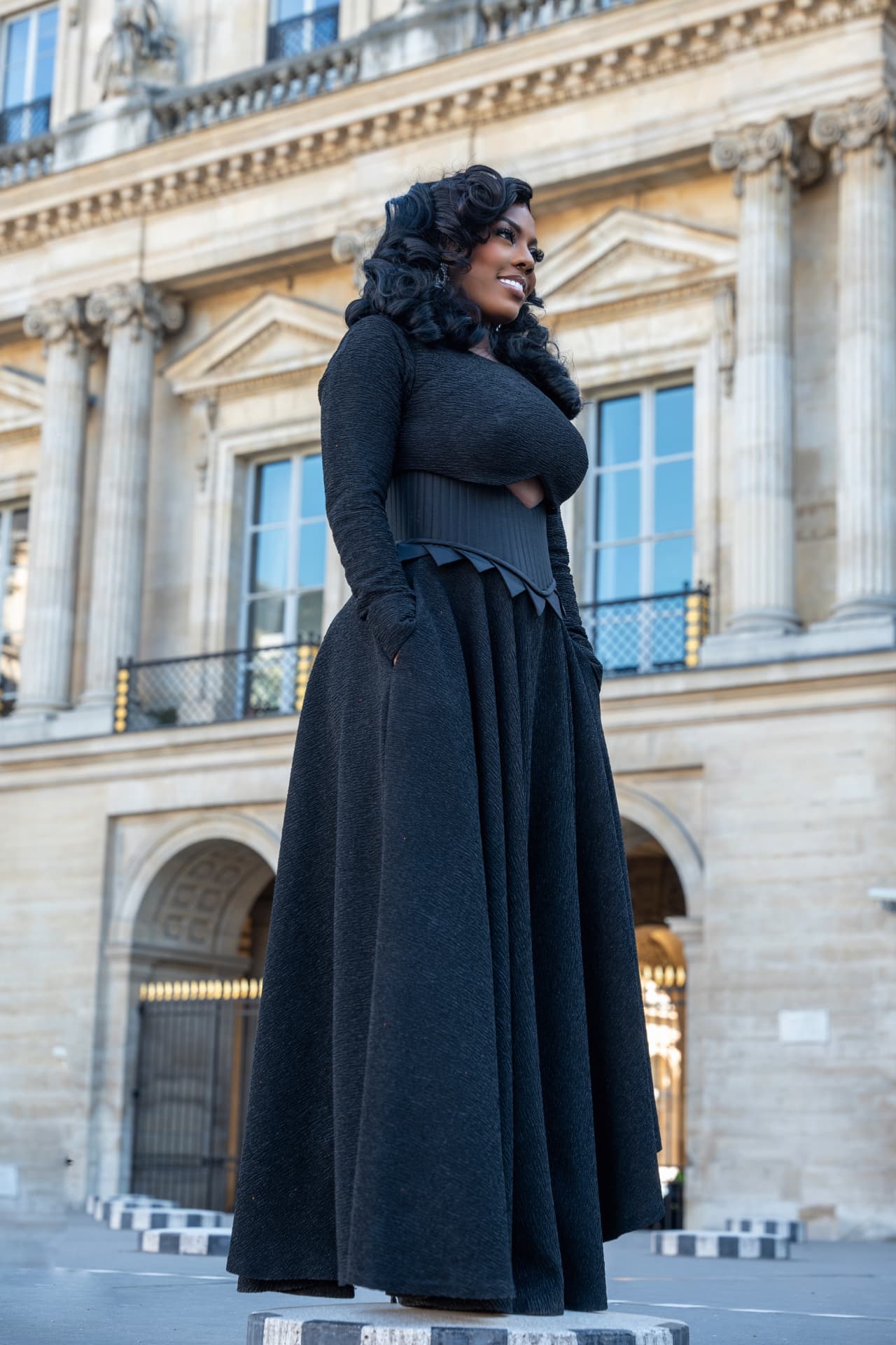 Nana Aba Anamoah in a black dress outside a columned building